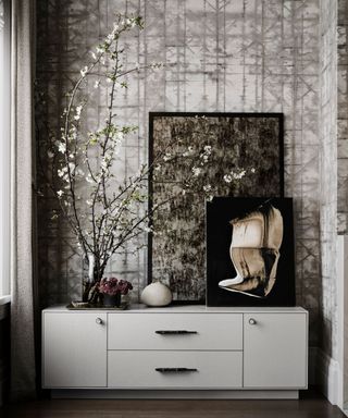 White and grey wallpaper, white drawers, plants