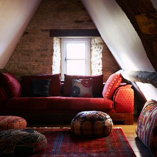 attic living room with stone wall window and red sofa with designed cushion