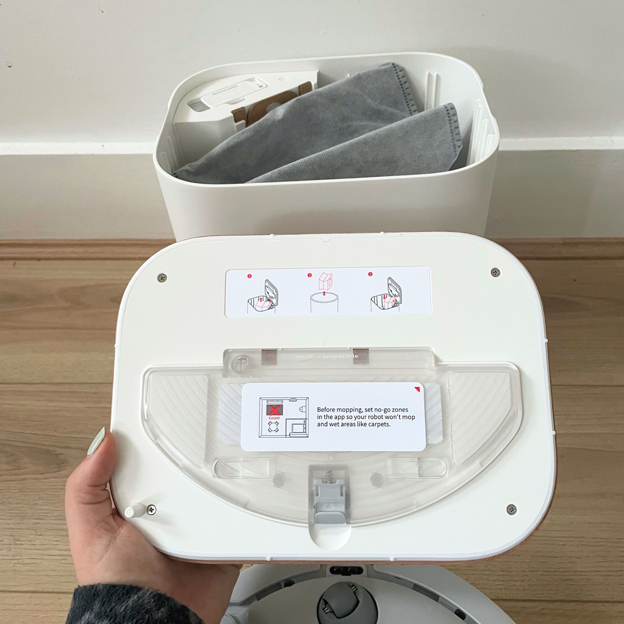 Hand holding the lid of the SwitchBot K11+ Robot Vacuum Cleaner with Mop