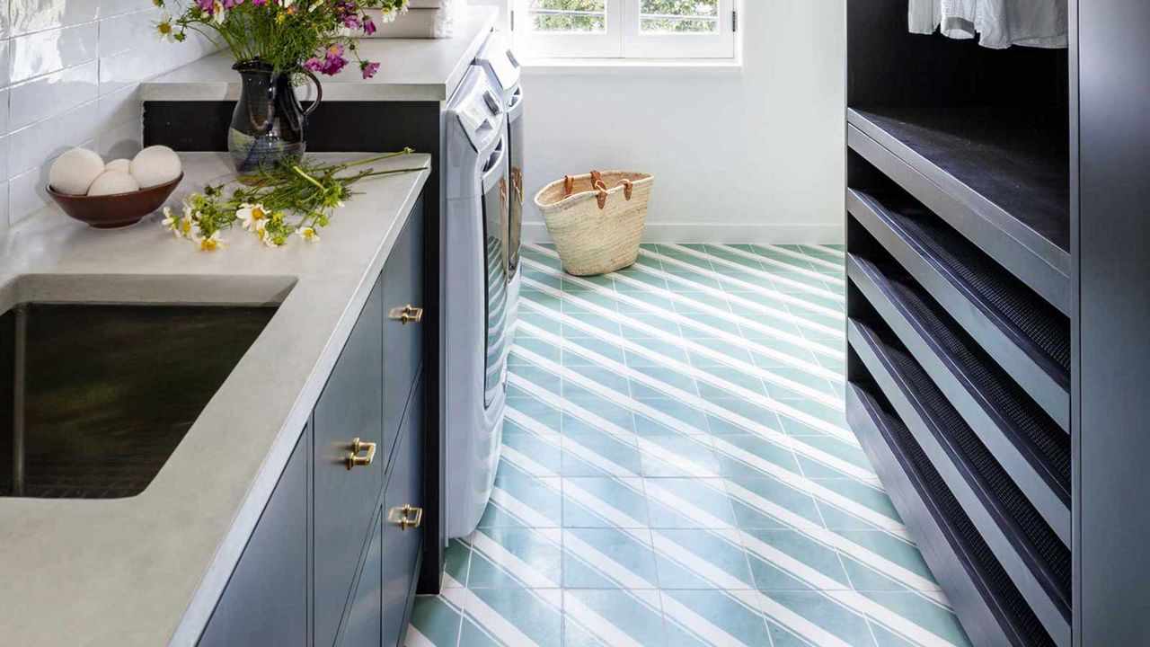 laundry room with green and white diagonal striped floor tiles. On the countertops is a vase with flowers. 