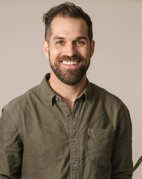 man with beard wearing khaki shirt and smiling