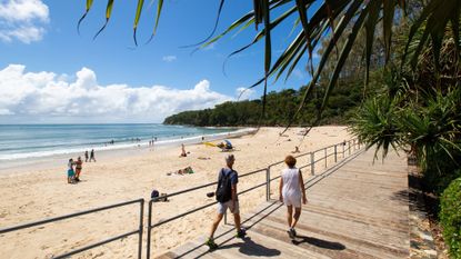 Noosa, Australia - a beach with people walking across the boardwalk