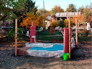 An outside makeshift boxing ring with mattresses for corner protectors.