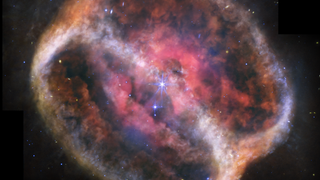 A pink hazy structure in space that looks like two overlapping rings, much like a Venn diagram.