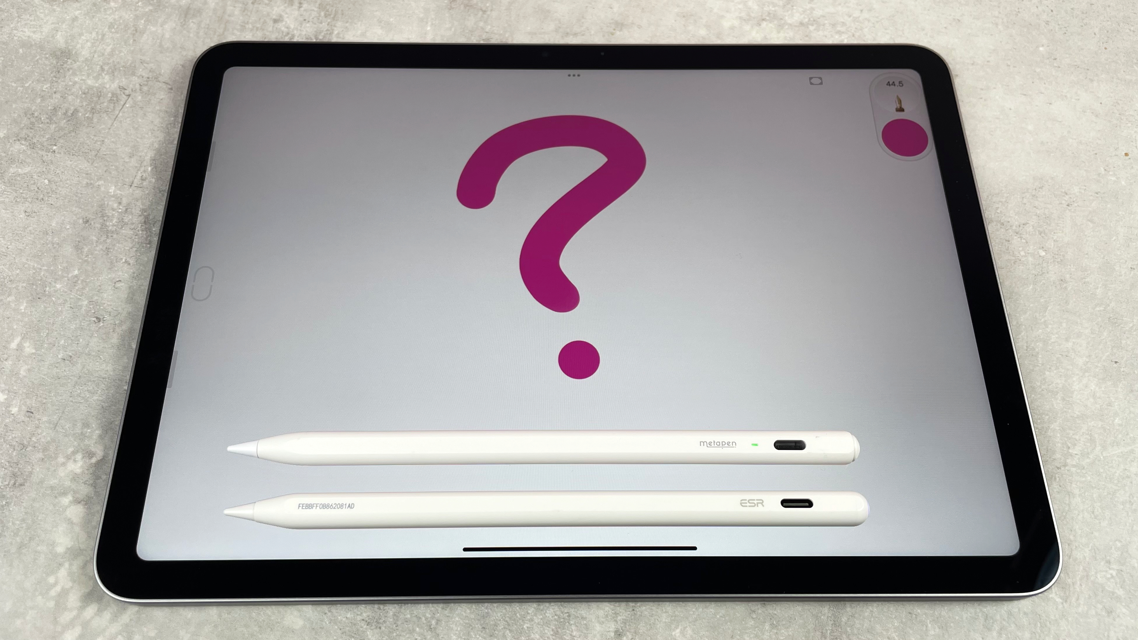 The ESR Geo Digital Pencil and the Metapen Pencil Air8 are placed one above the other on top of an iPad screen, which displays a pink question mark.