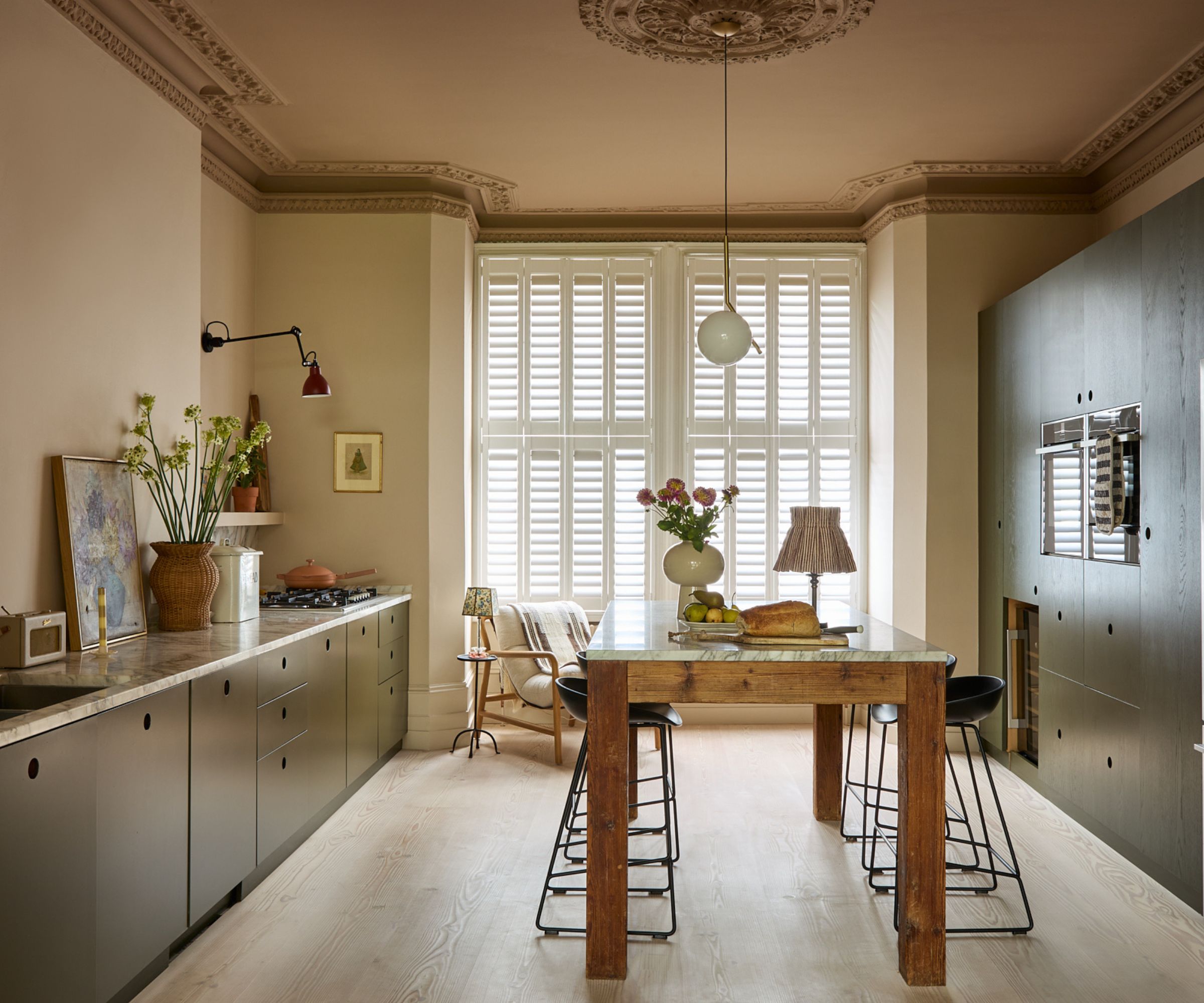 A large galley kitchen with dark green cabinets and a wooden freestanding island at the center