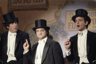 Elliott Gould in an snl skit with john beluschi and bill murray wearing top hats and singing