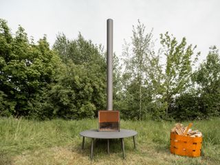 Black stove in a garden with an orange basket of logs