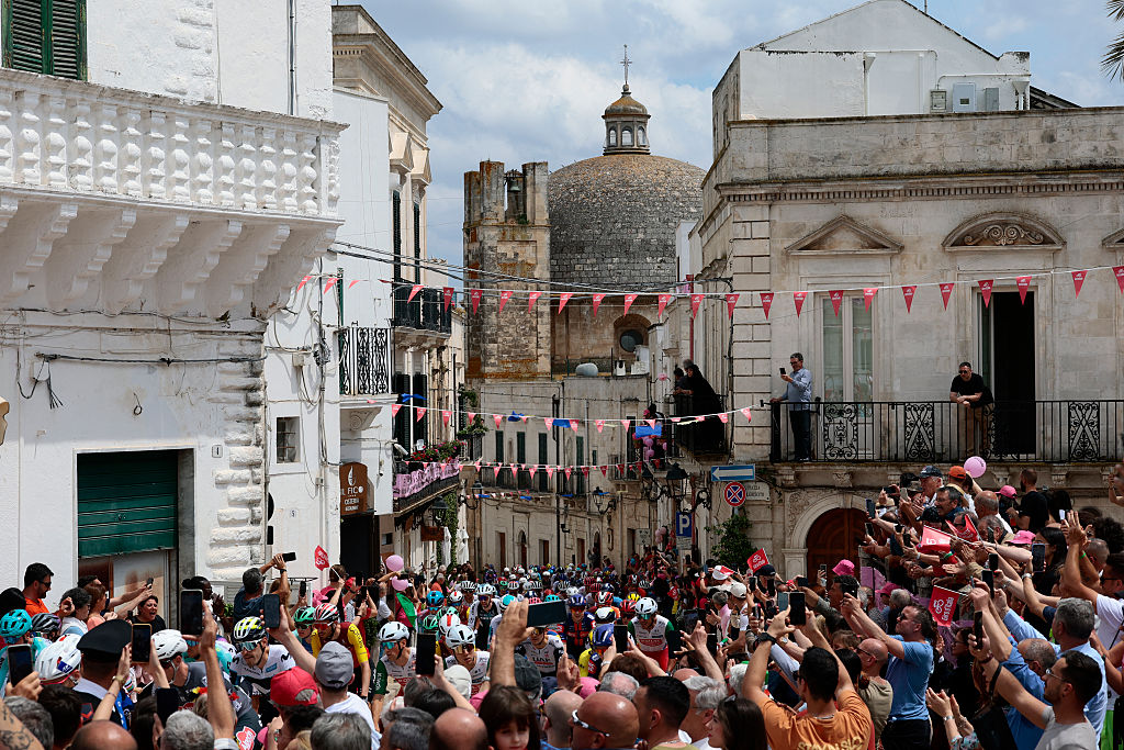 Riders are surrounded by the crowd on their way to reach the starting line of the 5th stage of the 108th Giro d'Italia cycling race 151kms from Ceglie Messapica to Matera on May 14, 2025. (Photo by Luca Bettini / AFP)