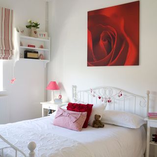 white bedroom with red rose frame on wall and pillows