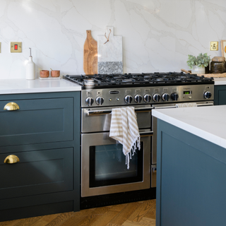 Mordern kitchen with silver oven. There are drak blue cupboards and white countertops