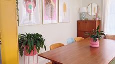 A brown dining table with colorful chairs next to it and ice cream wall art on the wall