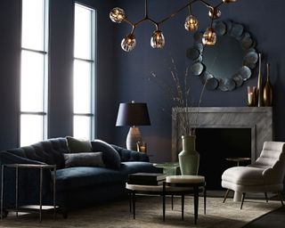 A dark grey Arteriors Shawnee living room with dark grey sofa, table lamp and metal ceiling light.