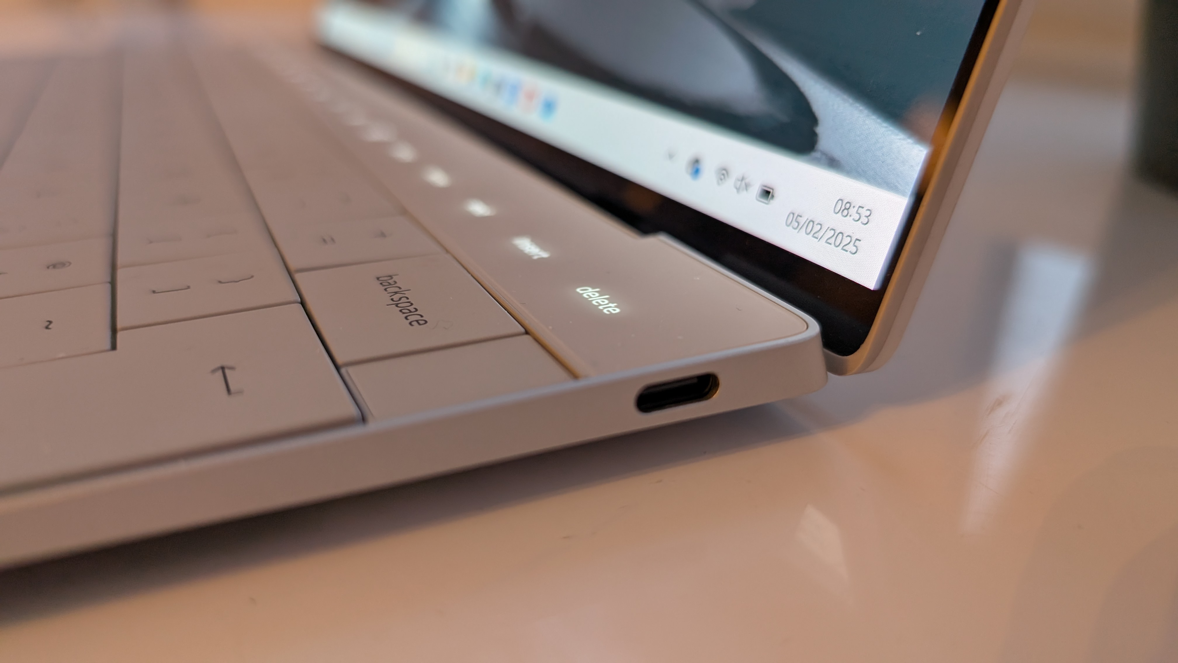 The Dell XPS 13 pictured on a white surface in front of a window with two potted plants.