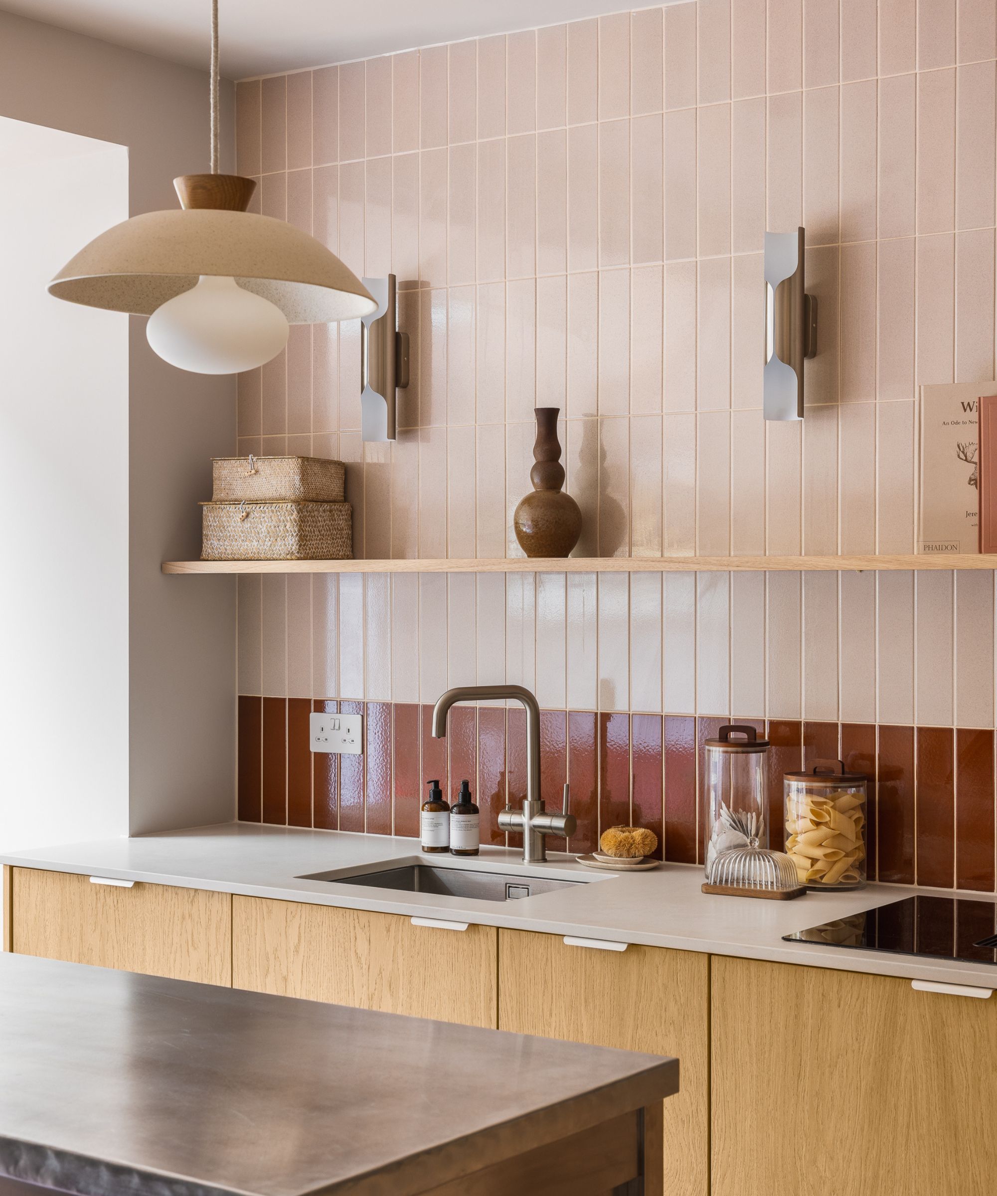 A kitchen with wooden cabinets, a white countertop, and pink wall tiles