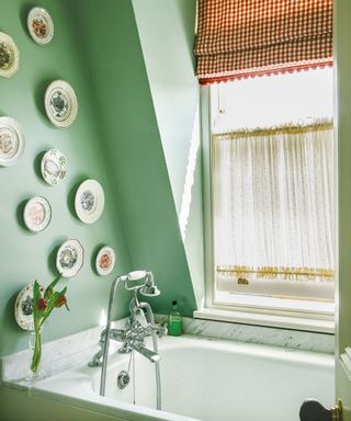 Blue bathroom with plates decorated on walls, white bath, windows with sheer curtains