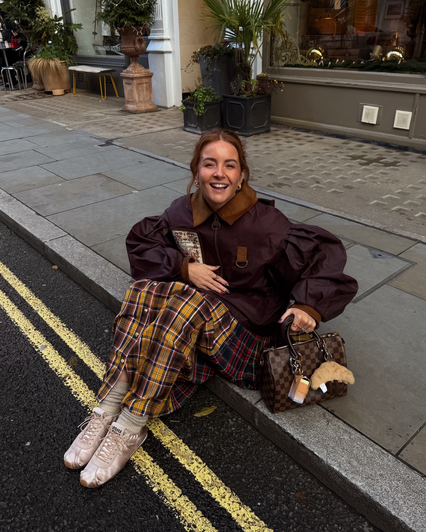 Woman in satin ballerina sneakers, a plaid skirt, and barn jacket