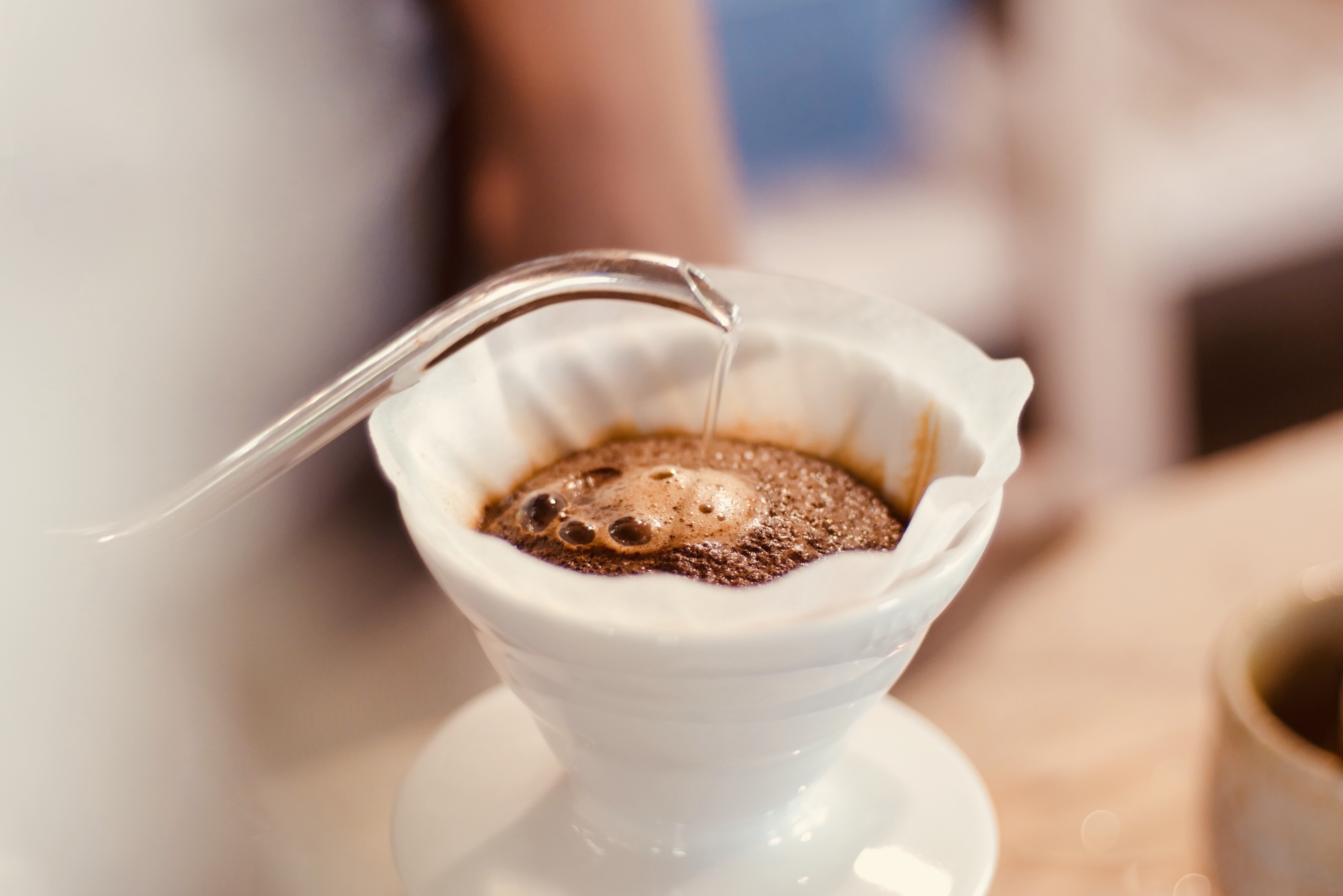 Le marc de café fleurit dans une coulée sur le goutteur de café alors que de l'eau est versée dessus