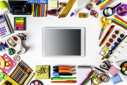 Back to school themes Overhead shot of back to school office supplies on white background with digital tables inside frame
