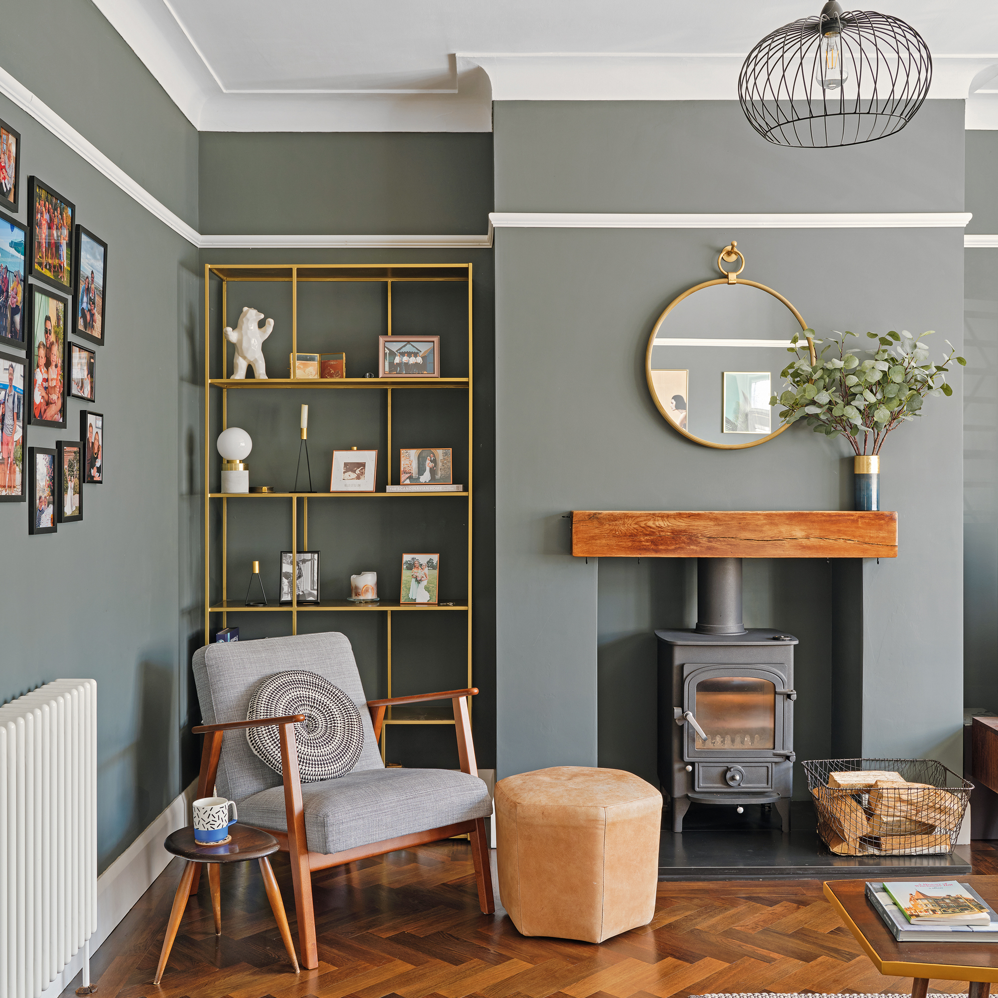 a green grey living room with an armchair, woodburner and parquet flooring
