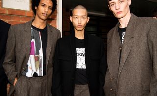 A row of four models pose for pictures against a brick backdrop