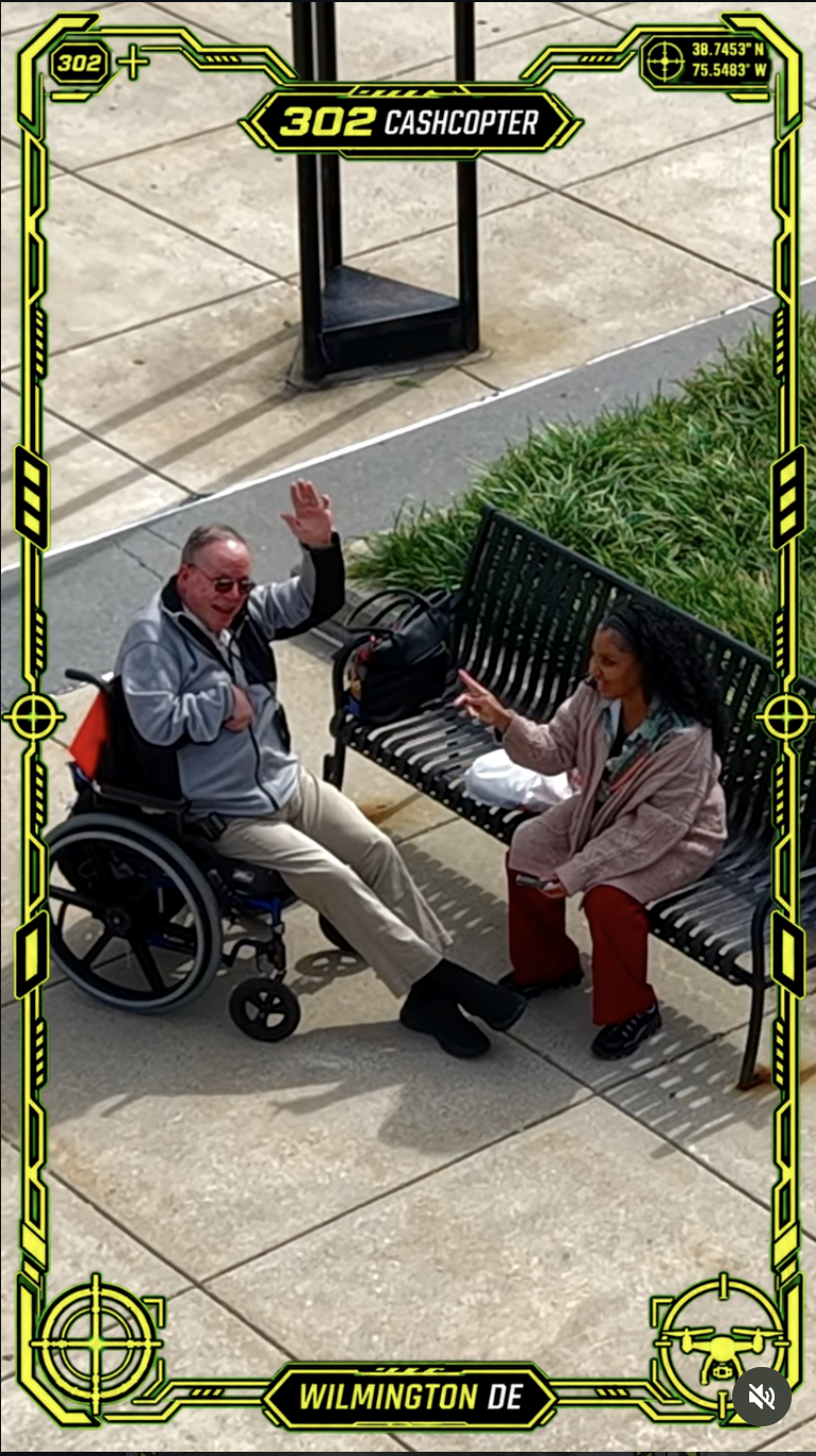 Man in wheelchair waving and other person on streets of Willmington, DE