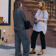 Women talk and are wearing similar outfits outside of a restaurant