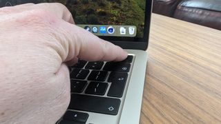 MacBook Air 13" (M3, 2024) puisella kahvipöydällä, ihminen painamassa nappia