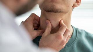 man getting his thyroid checked by the doctor