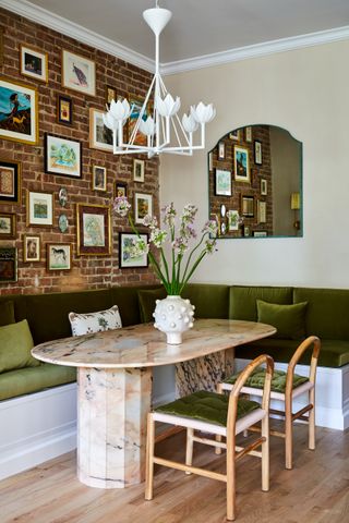 A small corner of the dining room with a green built-in bench and artworks on the wall