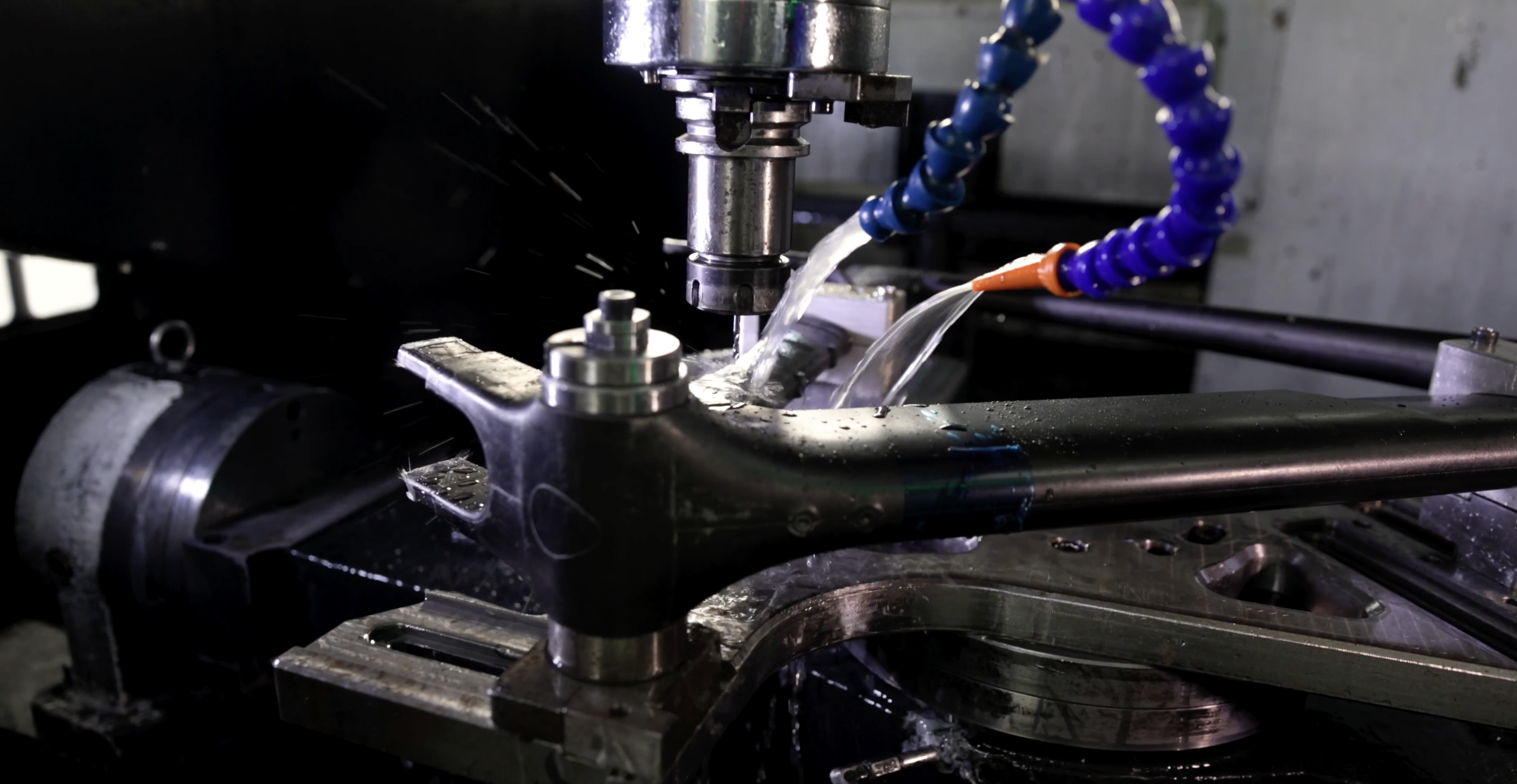 A CNC machine drilling a black carbon bike frame