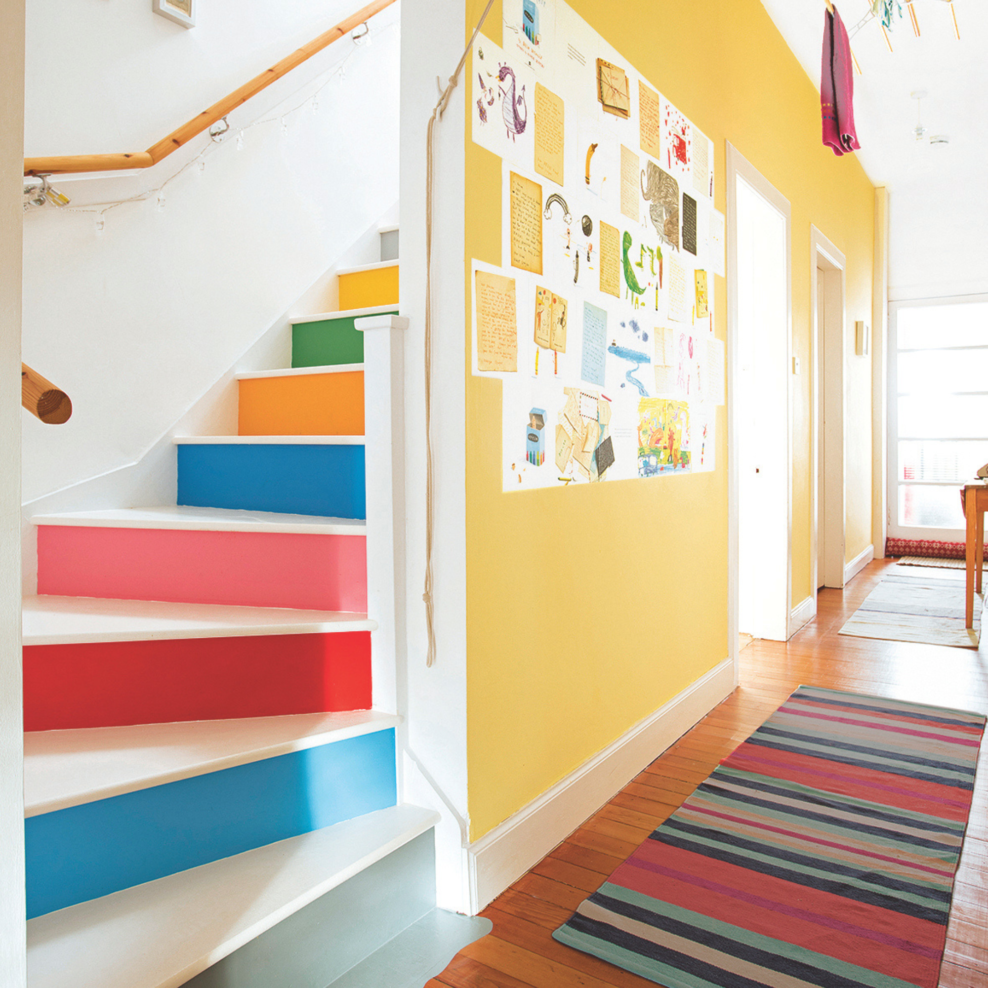 White painted hallway with wood stairs, and painted riser panels and a feature yellow wall.