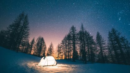 A tent pitched up in the snow in the woods