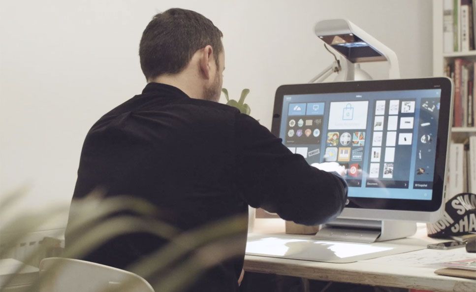 Man sitting at a desk with a computer and lamp