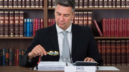 picture of IRS auditor examining documents with a magnifying glass
