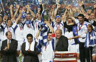 Theo Zagorakis lifts the European Championship trophy as Greece players celebrate victory over Portugal in the final of Euro 2004.