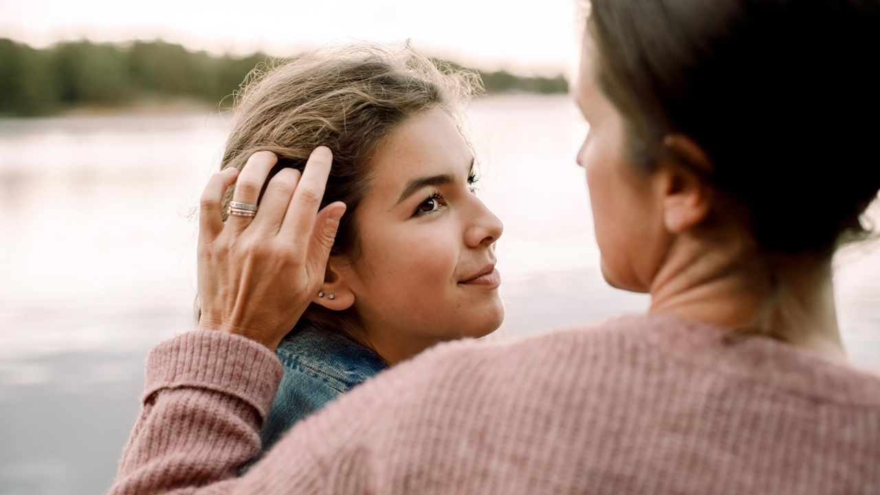 A mom brushes away hair out of her daughter&amp;#039;s face.