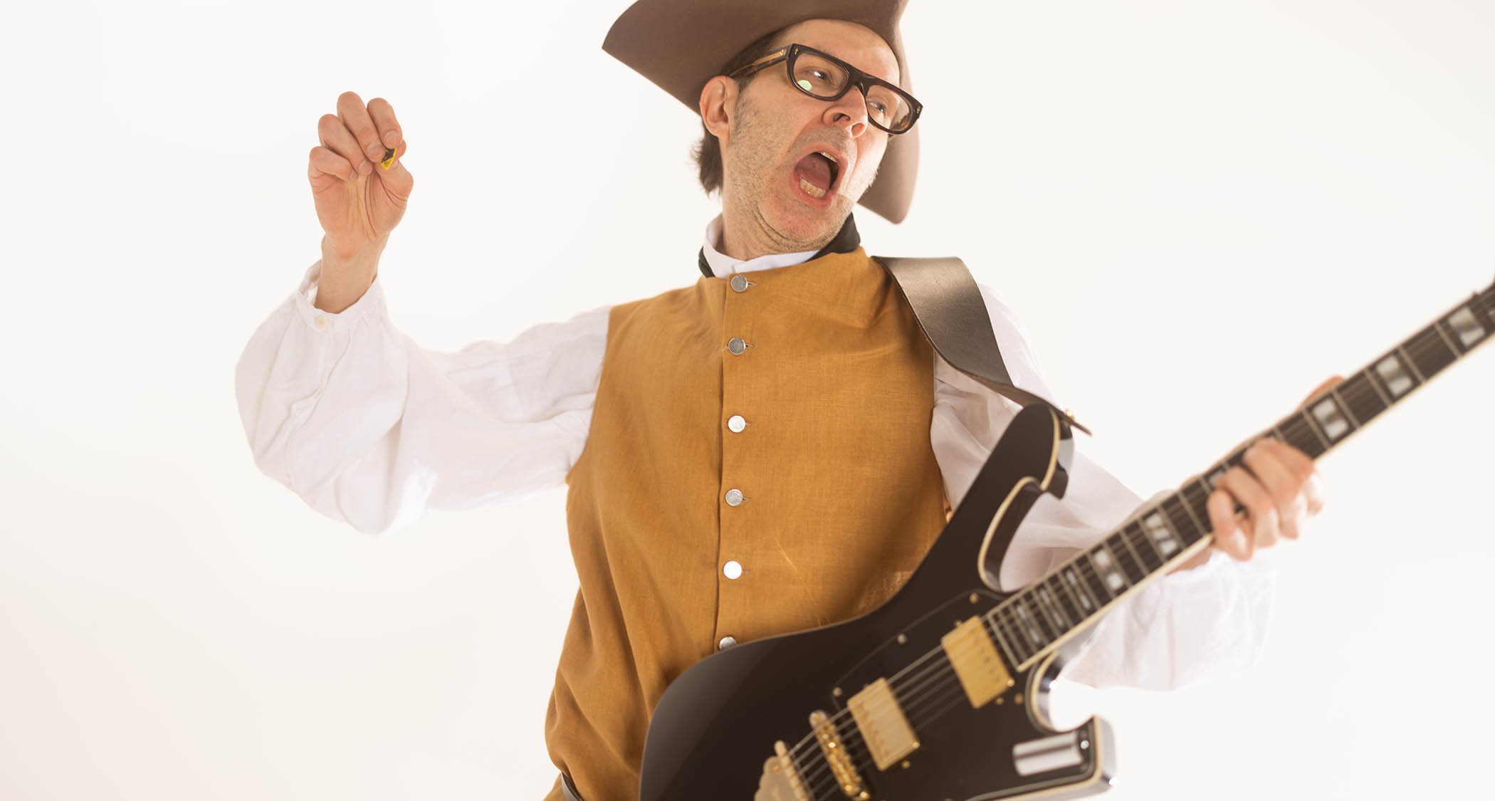 Paul Gilbert wears a tricorn and period dress as he poses in shred mode with his signature Ibanez guitar