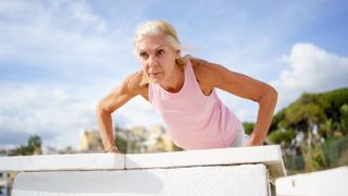 woman doing a push up on an outdoor bench