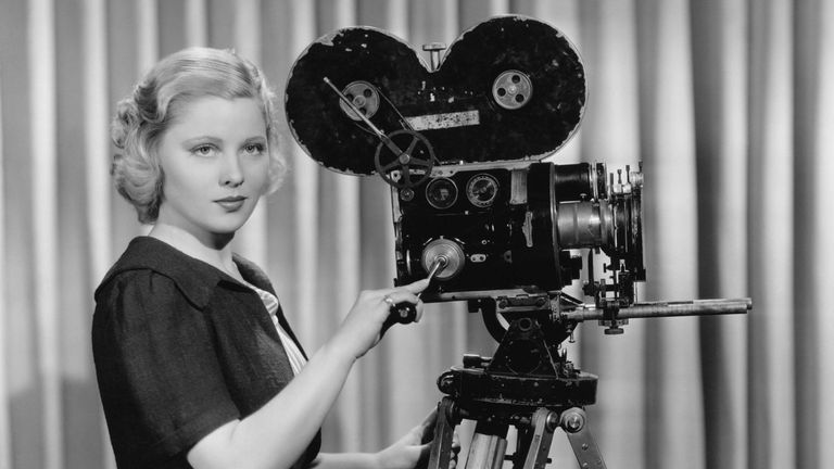 Woman operating old movie camera.