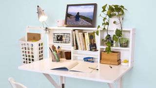 Haotian white folding desk with stationary, books and a plant