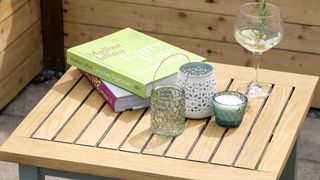 garden coffee table with tealight holders, candles, books and glass of Gin and tonic