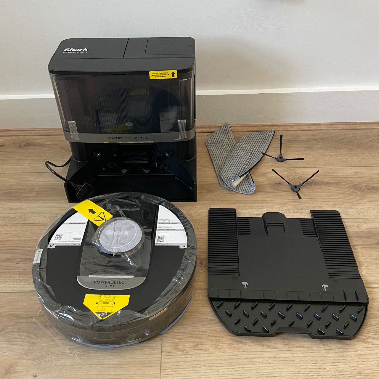 Components of the Shark robot vacuum cleaner and mop on wooden floor