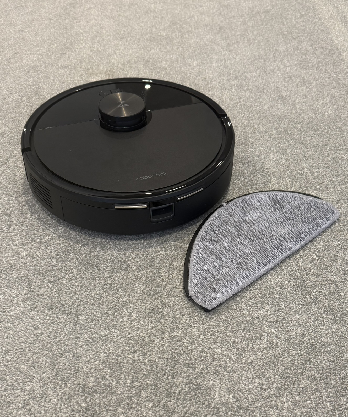 Roborock Q7 M5 next to mop pad on gray carpet in Victoria Woollaston&#039;s home.