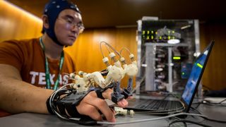 A student at Texas Robotics shows a brain-computer interface that enables him to control his hand with his thoughts.