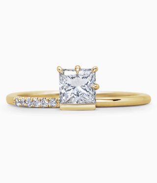 Michelle Oh Ring with a slim gold band with a square diamond and six small diamonds on adjacent.