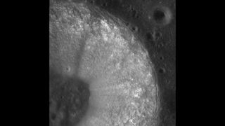 A classic bowl-shaped lunar crater known as Chladni crater in the Sinus Medii. The image shows the crater's ejecta blanket and part of its lumpy, crater-pocked floor.