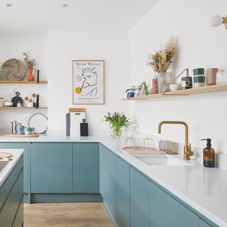 blue kitchen with white tops and open shelves lined with crockery and vases