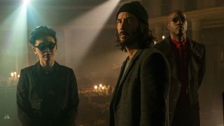 Jessica Henwick Keanu Reeves and Yahya Abdul-Mateen II standing in an old theater in The Matrix Resurrections.
