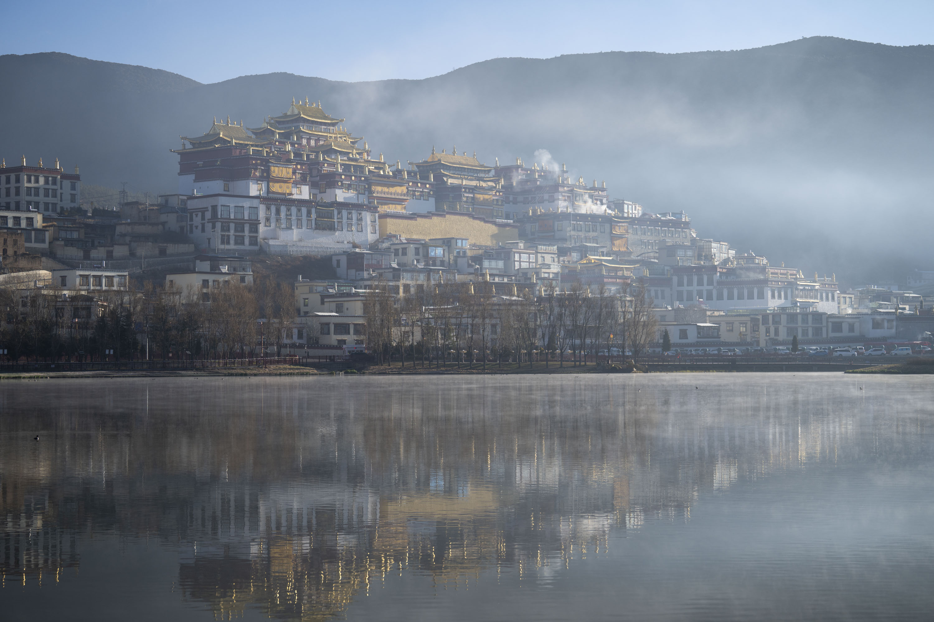A buddhist moonastery and town reflected in a still lake at first light